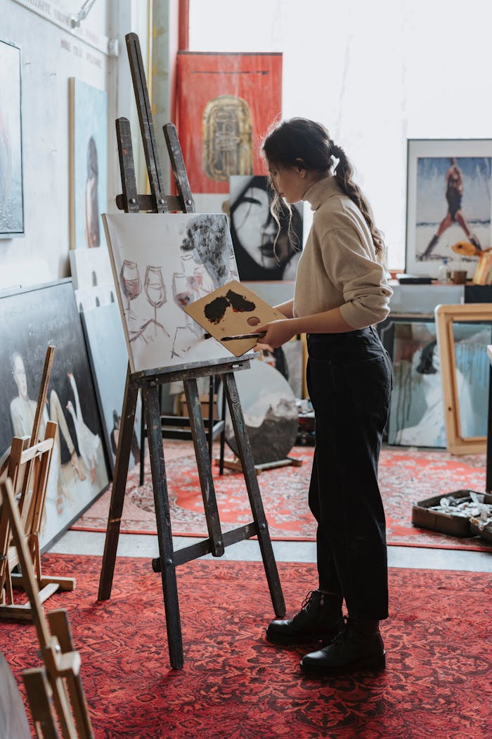 Mastering the First Impression: Your intriguing post title goes here Female artist painting on canvas in a vibrant studio space, showcasing creative process.